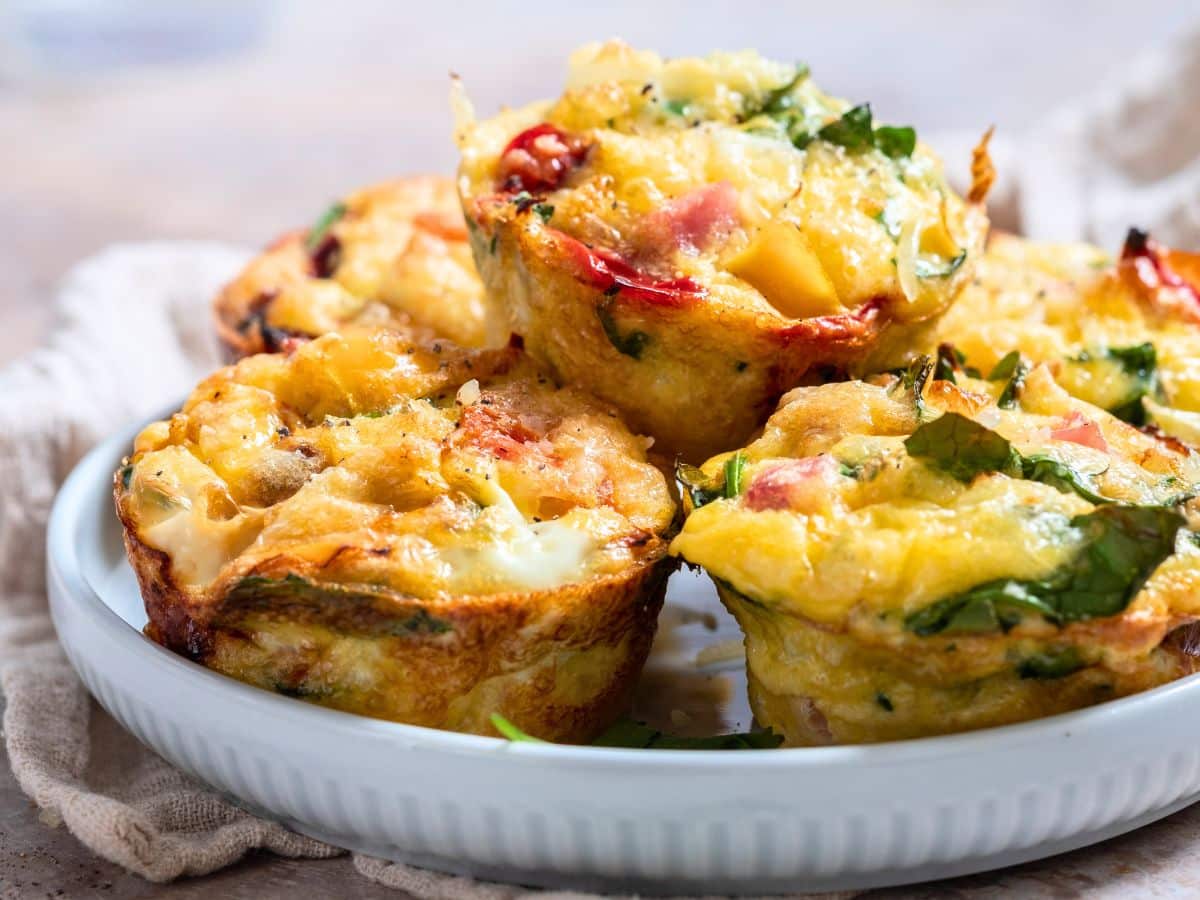 Mini frittata muffins stacked on a plate.