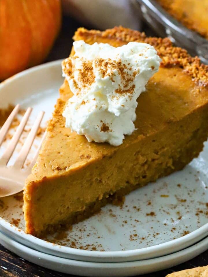 A slice of Pumpkin pie with whipped cream on top.