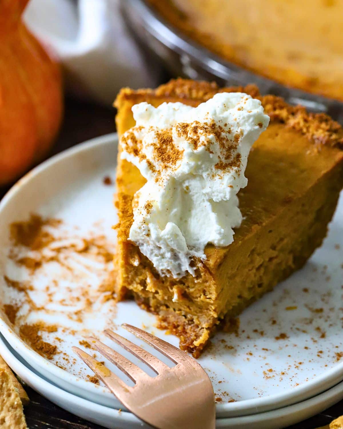 Pumpkin pie with whipped cream on top and a bite out.