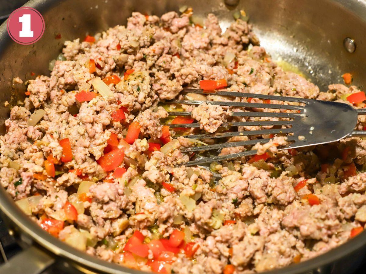 A skillet with cooked Italian sausage, onions,  and peppers.