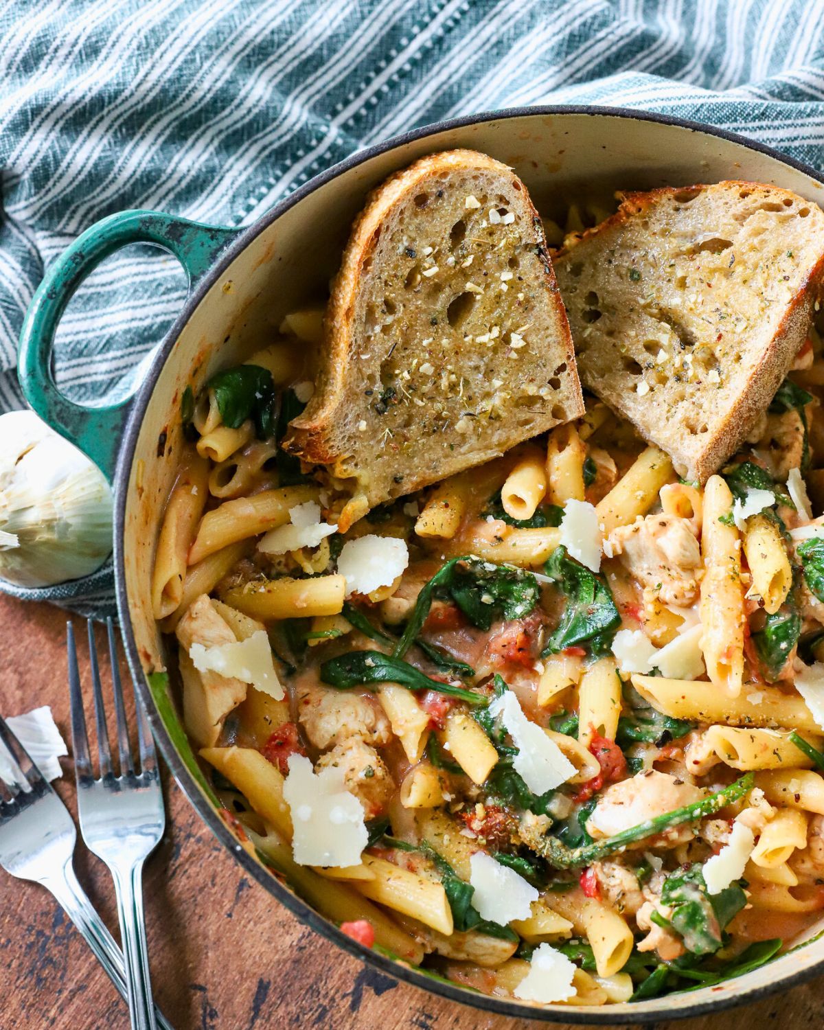 Pot full of chicken pasta with spinach and Parmesan cheese.