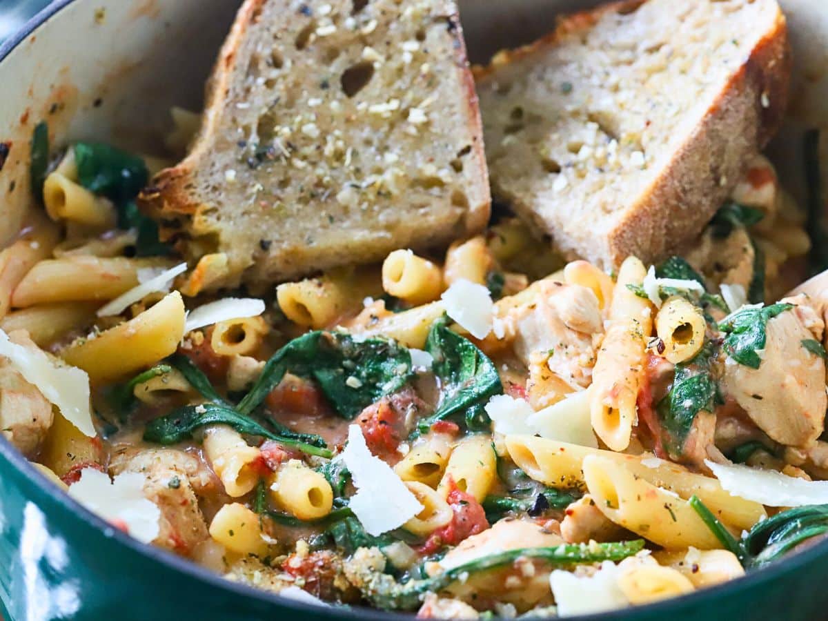 Close up of chicken pasta in a pot with Parmesan cheese.