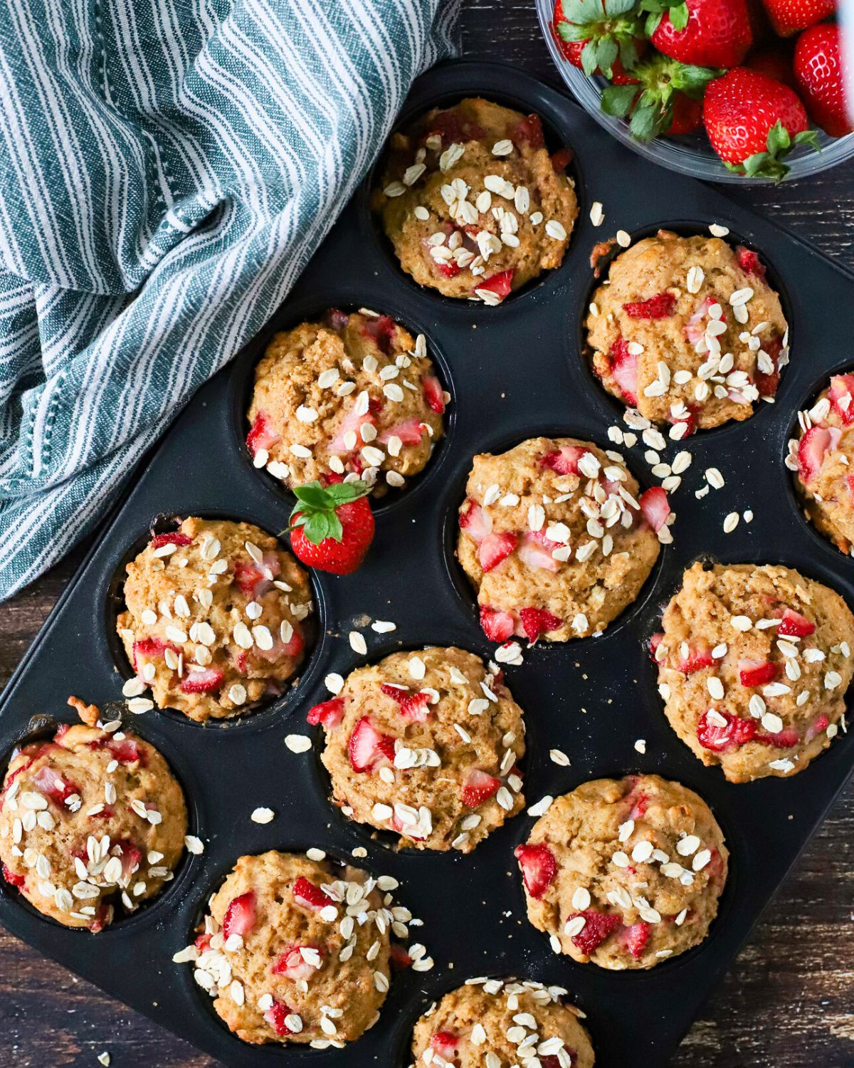 Muffin pan filled with fresh baked muffins with strawberries.