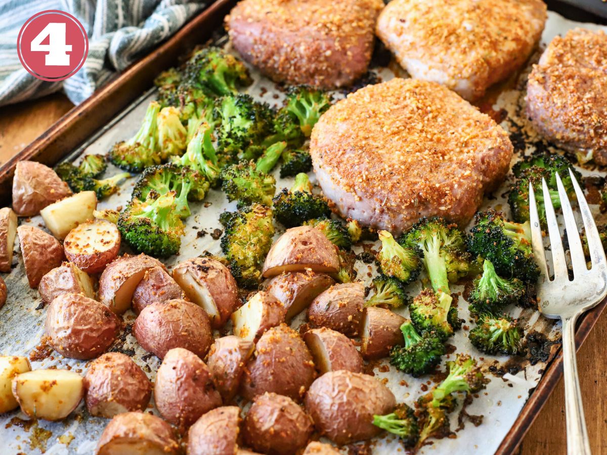 A sheet pan full of baked pork chops, potatoes, and broccoli.