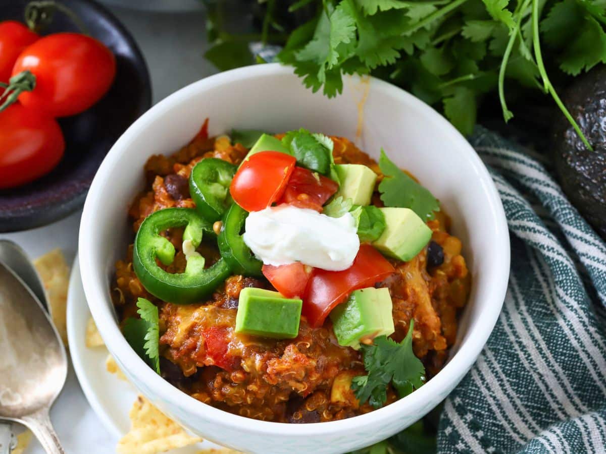 Bowl filled with a ground beef casserole topped with jalapenos and avocaco.