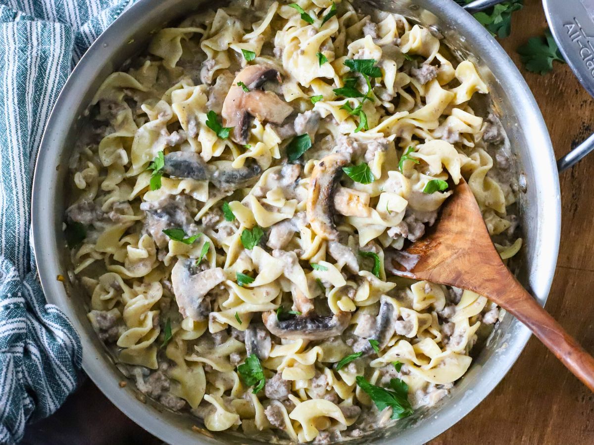 Pan filled with noodles, ground beef, sauce and mushrooms.