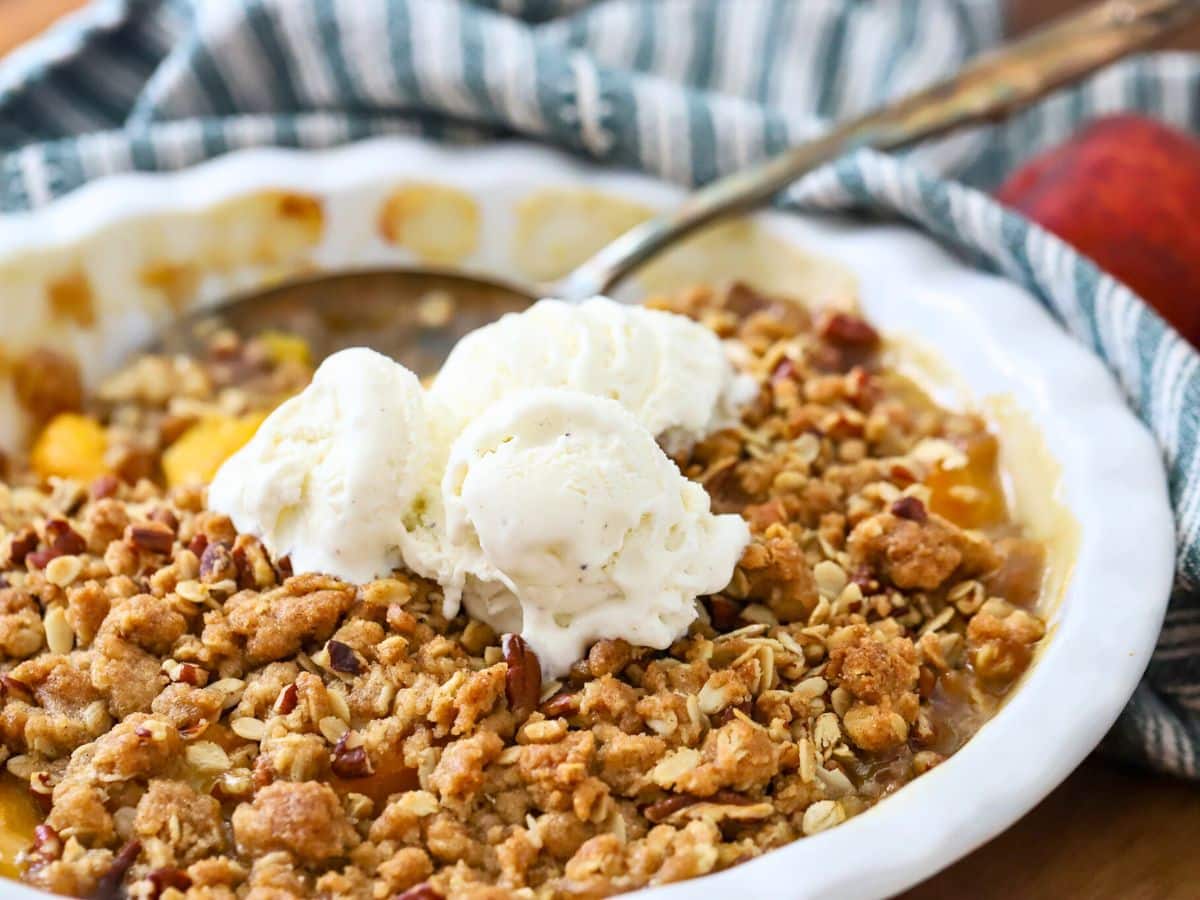 A homemade peach crisp with scoops of ice cream on top.