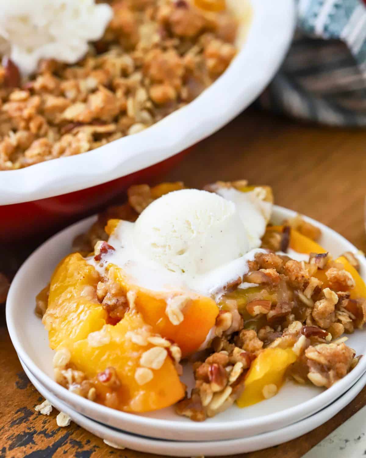 A small plated with peach crisp topped with vanilla ice cream.