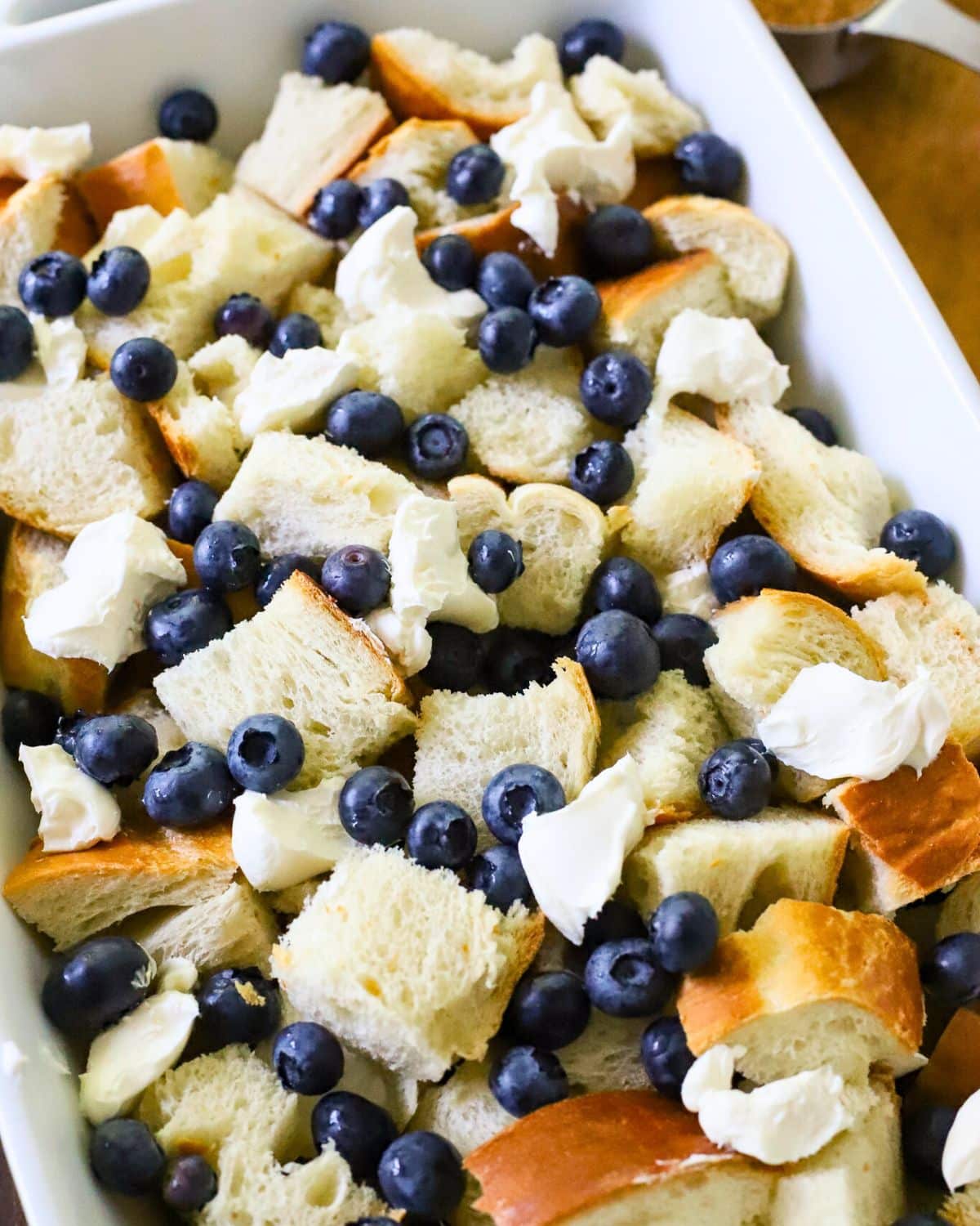 Baking dish filled with bread, blueberries, and cream cheese.