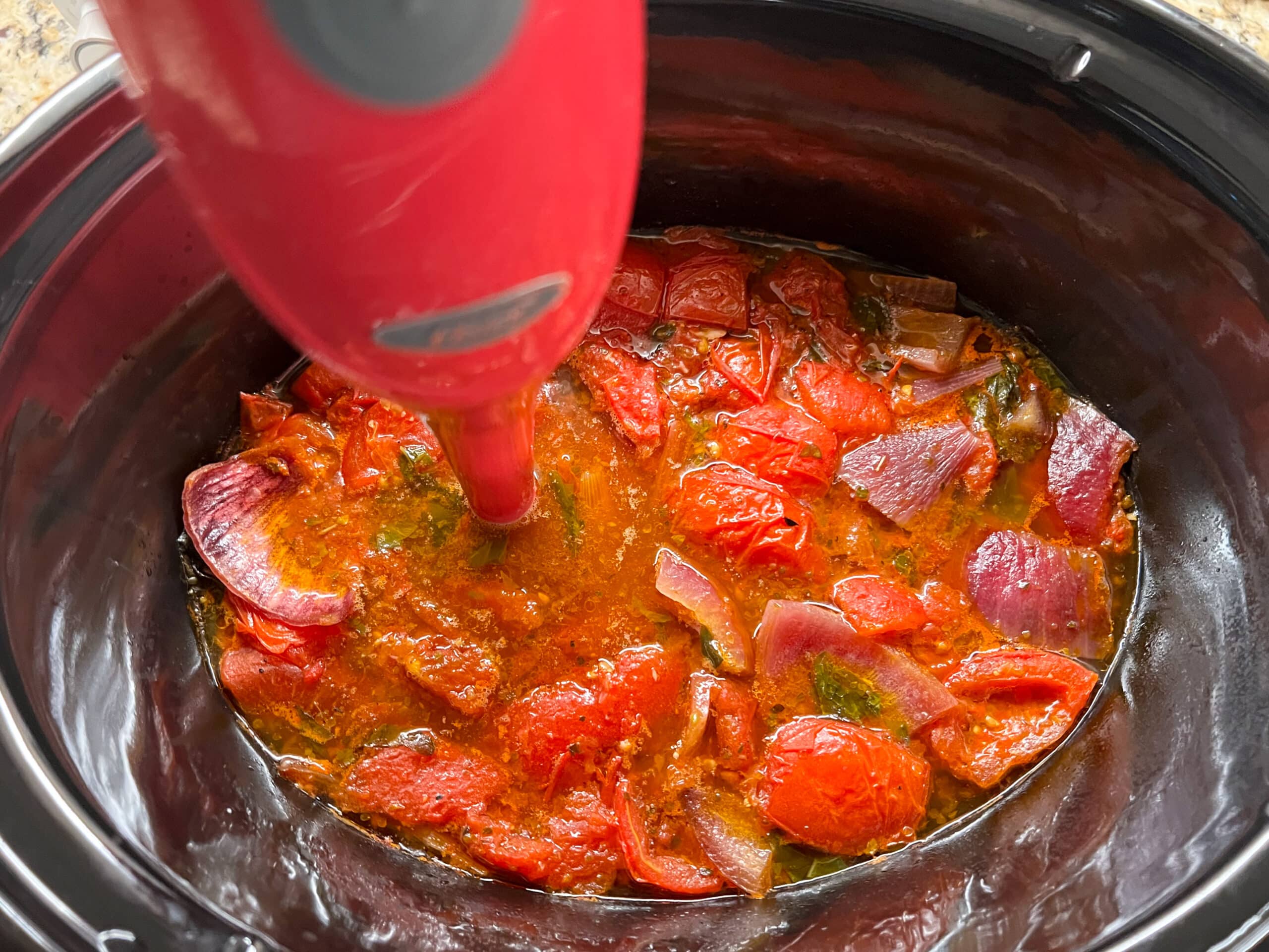 Tomato Basil soup ingredients in slow cooker with immersion blender