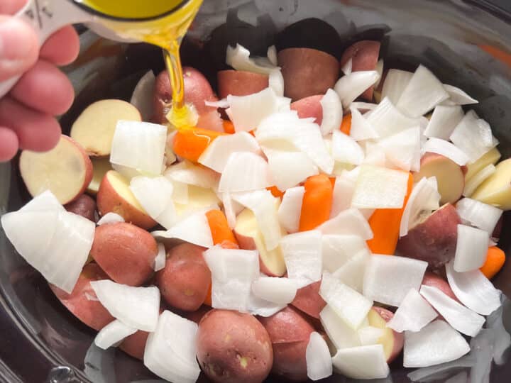 Prepped veggies in slow cooker with olive oil