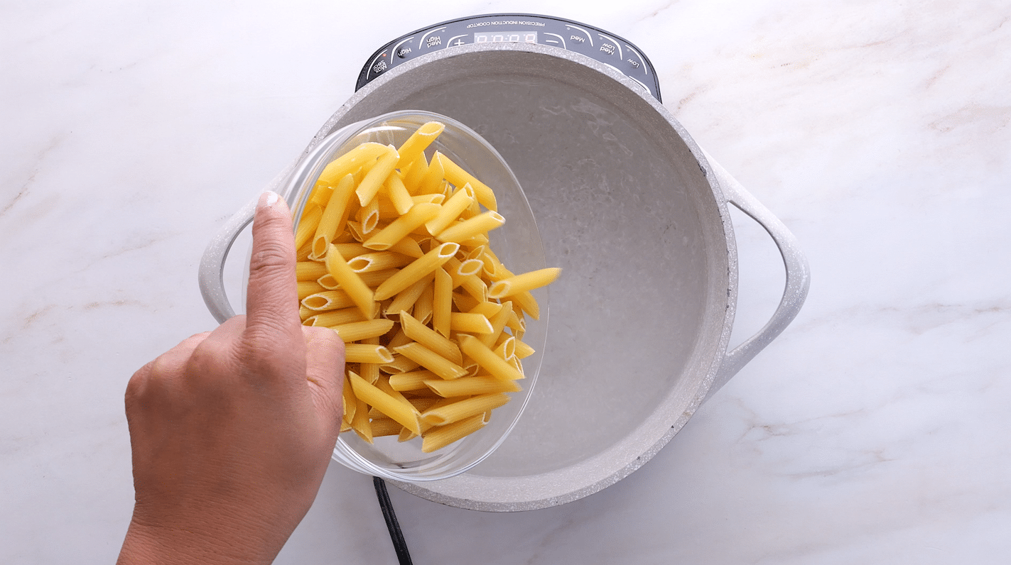 Pouring penne pasta into salted water