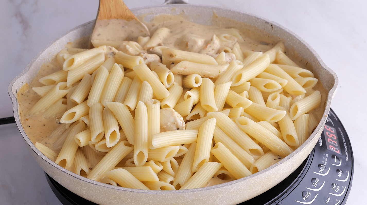 Penne pasta and chicken pieces added back into skillet with sauce